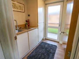 A small utility room with a sink fridge fire extinguisher and a door with frosted glass at Finnbars Lodge in Richmond