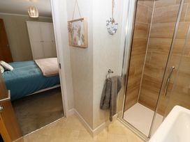 A bathroom with a shower and towel hanging on the wall next to a bedroom with a bed and wardrobe at Finnbars Lodge Richmond