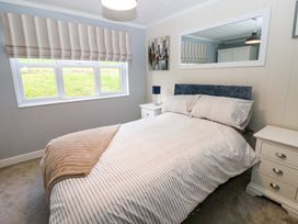 A bedroom with a double bed striped bedding bedside tables and a window with striped blinds at Finnbars Lodge Richmond