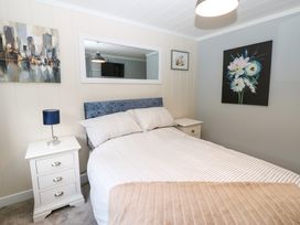 A bedroom with a bed between two bedside tables each with a lamp and wall art at Finnbars Lodge in Richmond
