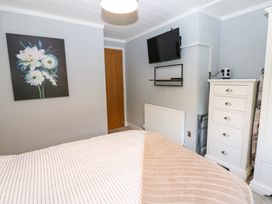 A bedroom with a bed radiator wooden door wall-mounted tv chest of drawers and a floral painting at Finnbars Lodge in Richmond