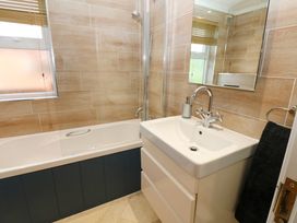 A bathroom with a bathtub shower combination a white sink with a faucet a mirror and a towel at Finnbars Lodge Richmond