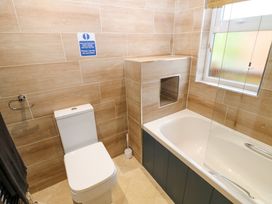 A bathroom with a toilet and a bathtub next to a frosted window at Finnbars Lodge Richmond