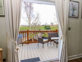 A balcony with wicker chairs and a table overlooking a green field at Finnbars Lodge in Richmond