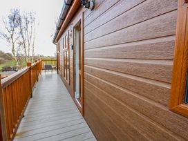 A wooden balcony with a railing and outdoor furniture at Finnbars Lodge in Richmond