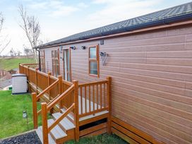An exterior view of a single story building with wooden siding and a wooden deck with stairs at Finnbars Lodge in Richmond
