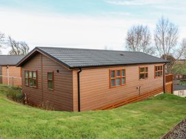A brown single story cabin with multiple windows on a grassy slope at Finnbars Lodge in Richmond