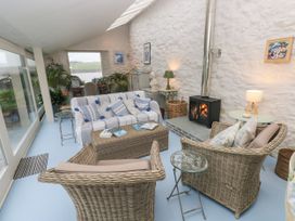 A conservatory with a sofa and armchairs at Curlew House in Cosheston