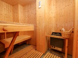 A sauna with wooden benches and a wood stove at Curlew House in Cosheston