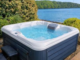 A hot tub by the water in the garden at Curlew House Cosheston