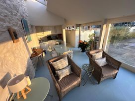 A living room with seating and kitchen area at Curlew House in Cosheston