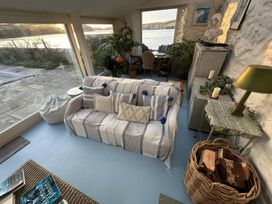 A conservatory with a sofa and plants at Curlew House in Cosheston