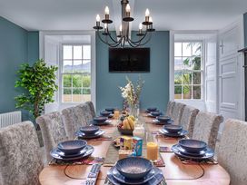 A dining room with a long table and chairs at Snowdonia Manor in Dolgellau