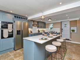 A kitchen with a countertop, refrigerator, and bar stools at Snowdonia Manor in Dolgellau