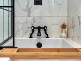 A bathtub with a black faucet and decorative vase in the bathroom at Snowdonia Manor in Dolgellau