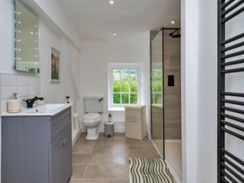 A bathroom with a sink, toilet, shower, and window at Snowdonia Manor in Dolgellau