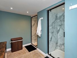 A bathroom with a shower, laundry basket and towel at Snowdonia Manor in Dolgellau