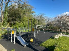 A playground with slides, swings, and benches at Swallows Reach in Halwell