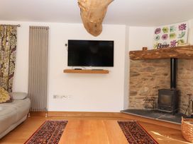 A living room featuring a sofa, television, and wood burner at Swallows Reach Halwell
