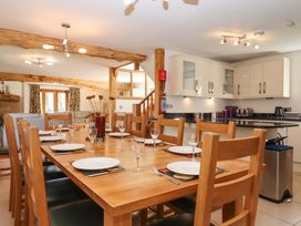 A dining area with a wooden table and kitchen cabinetry at Swallows Reach Halwell
