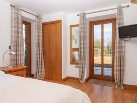 A bedroom with a bed, a lamp, and a television at Swallows Reach in Halwell