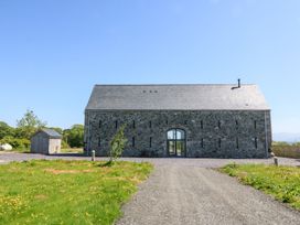 A stone barn with a pitched roof and arched entrance at Tithe Barn in Capel Mawr near Malltraeth