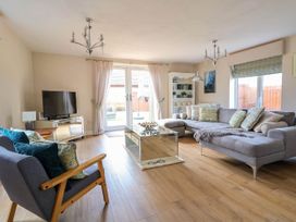 A living room with a gray sofa a wooden armchair and a glass coffee table at Brimrod in Talacre