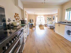A kitchen area with stove toaster microwave and washing machine leading to a living room with sofa armchair TV and coffee table at Brimrod in Talacre