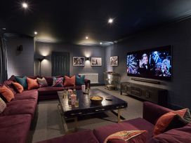 A home theater with a large sofa and television at Craig y Don Glyngarth near Llandegfan