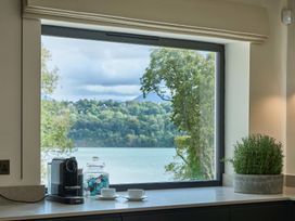 A kitchen with a window overlooking a lake at Craig y Don in Glyngarth near Llandegfan