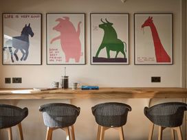 A kitchen with animal paintings on the wall and a bar counter at Craig y Don in Glyngarth near Llandegfan