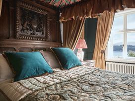 A bedroom with a detailed bed and window view at Craig y Don Glyngarth near Llandegfan