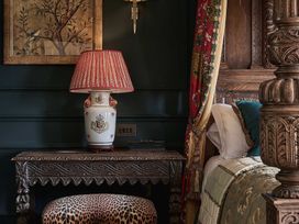 A bedroom with a decorative lamp and carved table at Craig y Don Glyngarth near Llandegfan