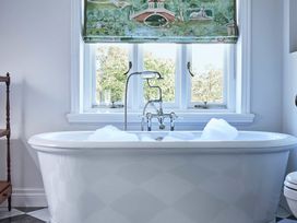 A bathroom with a bathtub and window at Craig y Don in Glyngarth near Llandegfan