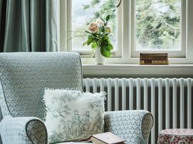 A living room with an armchair and books on a window sill at Craig y Don in Glyngarth near Llandegfan
