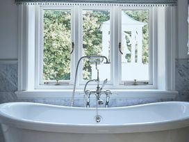 A bathtub with a faucet in front of windows at Craig y Don in Glyngarth near Llandegfan
