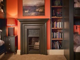 A bedroom featuring a lamp, nightstand, bookshelf and fireplace at Craig y Don Glyngarth near Llandegfan