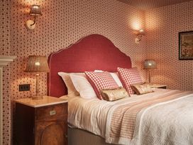 A bedroom with a bed featuring checked pillows and lamps at Craig y Don Glyngarth near Llandegfan