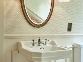 A sink and mirror in a bathroom at Craig y Don Glyngarth near Llandegfan