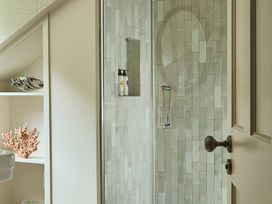 A shower with glass door and shelf in a bathroom at Craig y Don in Glyngarth near Llandegfan