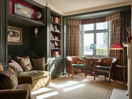 A snug with a bookshelf and seating area at Craig y Don in Glyngarth near Llandegfan