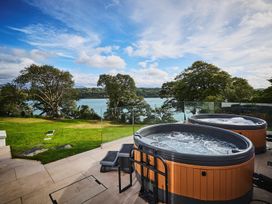 Two hot tubs with a view of water at Craig y Don in Glyngarth near Llandegfan