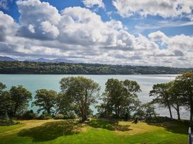 A view of a garden with trees and water at Craig y Don in Glyngarth near Llandegfan