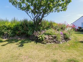 A garden with a flower bed and a tree at Bramble Cottage in Gwithian near Connor Downs