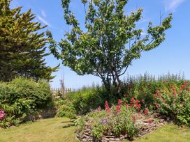 A garden with a tree and flower beds at Bramble Cottage in Gwithian near Connor Downs