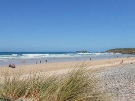 A beach with people enjoying the sun and waves at Bramble Cottage in Gwithian near Connor Downs