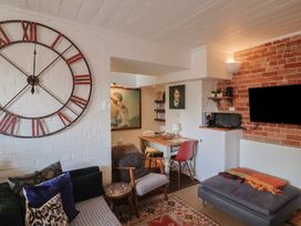 A living room with a clock on the wall and a sofa at The Clock Tower in Rousdon, Nr Lyme Regis