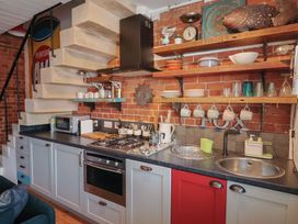 A kitchen with a sink, stove, and shelves at The Clock Tower in Rousdon, Nr Lyme Regis