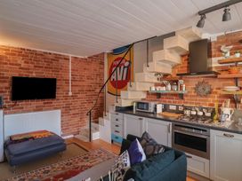 A living room with a kitchen area and stairs at The Clock Tower in Rousdon, Nr Lyme Regis