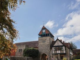 A clock tower with a building and trees at The Clock Tower Rousdon, Nr Lyme Regis
